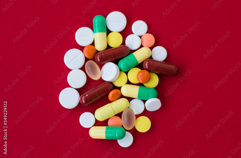 Medical background with pills and capsule on red background.Assorted pharmaceutical medicine pills, tablet. Heap of various assorted medicine tablets and pills different colors. Health care. Top view Medical background with pills and capsule on red background.Assorted pharmaceutical medicine pills, tablet. Heap of various assorted medicine tablets and pills different colors. Health care. Top view