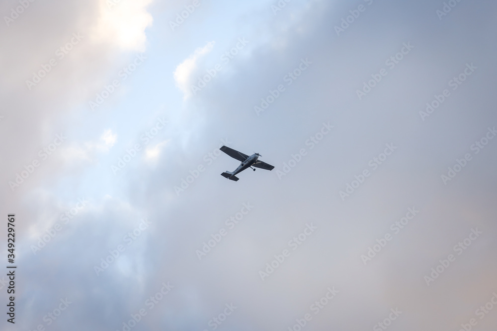 Fototapeta premium Small plane flying on the backgorund of clouds. Photo taken in cloudy day, Europe, Latvia.
