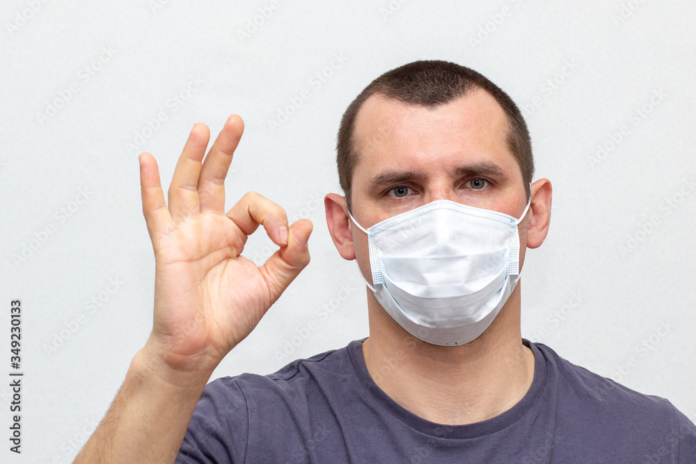 man in medical mask on his face showing ok on a white background. man in medical mask on his face showing ok on a white background.