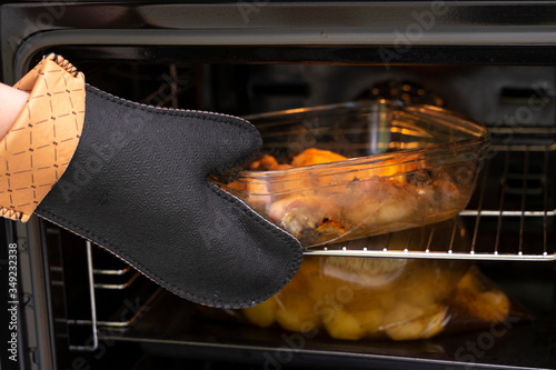 Fotografie hand in a refractory glove takes dinner out of the oven