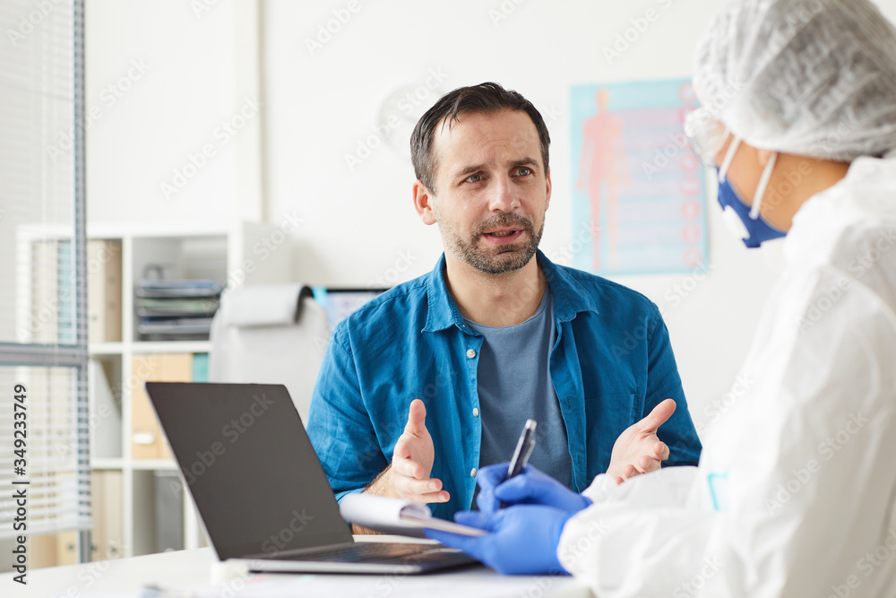 Mature man visiting his doctor he sitting and telling about his complaints at office Mature man visiting his doctor he sitting and telling about his complaints at office