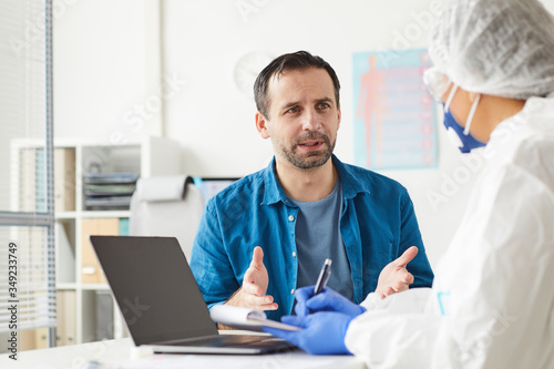 Mature man visiting his doctor he sitting and telling about his complaints at office
