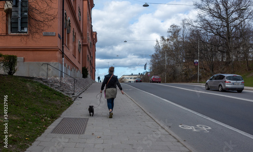 April 22, 2018, Stockholm, Sweden. A woman with a black dog on a leash on one of the streets in Stockholm.