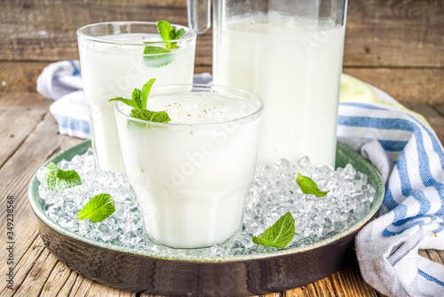 Cold Indian drink Lassi, iced coconut Lassi drink with mint leaf, wooden background copy space