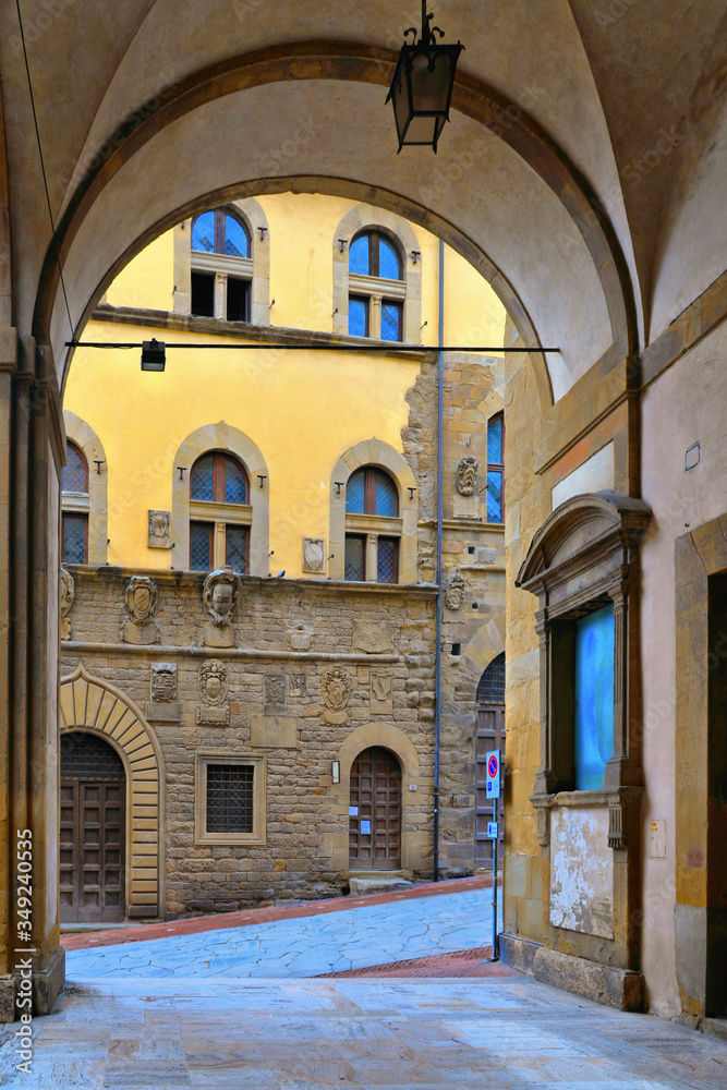 TUSCANY, AREZZO. Columns and arches in old narrow street in historical centerof Arezzo with facade of medieval buildings. Italy