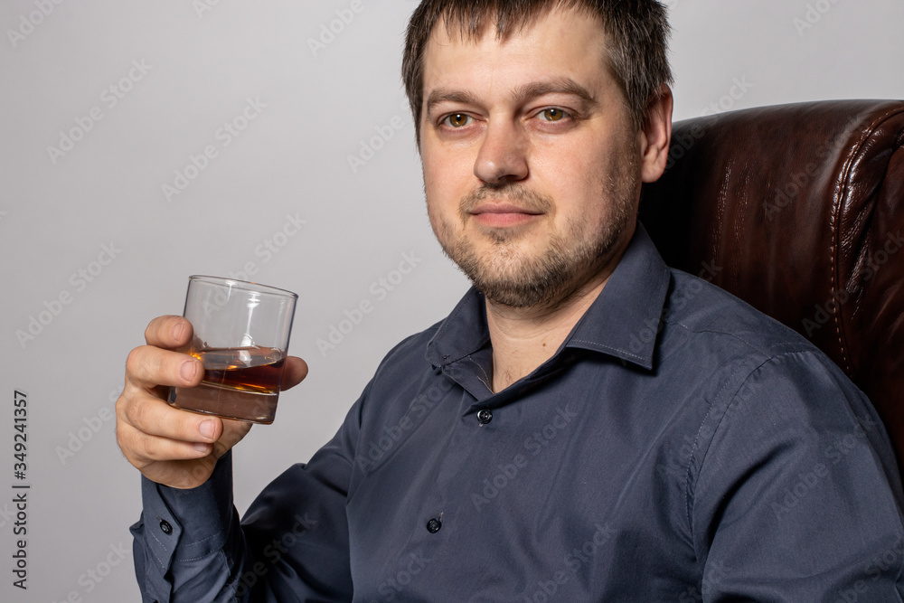 A 30-year-old man holds whiskey in a glass in his hand. Expensive alcoholic drink. A 30-year-old man holds whiskey in a glass in his hand. Expensive alcoholic drink.