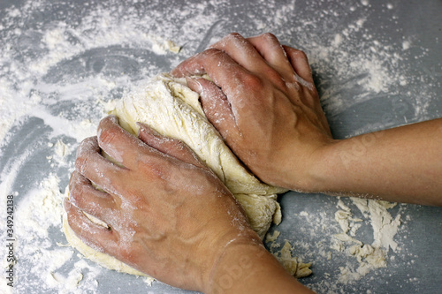 Woman hands kneading dough on the grey table