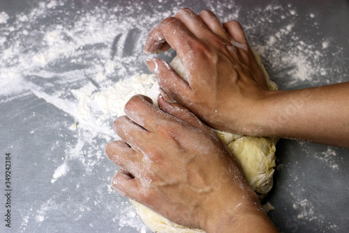 A woman kneads sweet yeast dough on the grey table