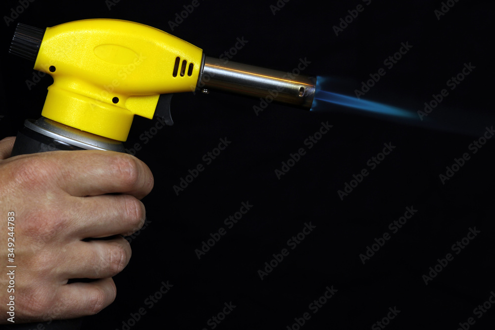 manual gas burner with blue flame on a black background