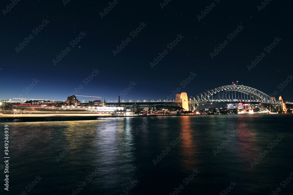Long exposure of a ship crossing harbour bridge in Sydney night time with stars