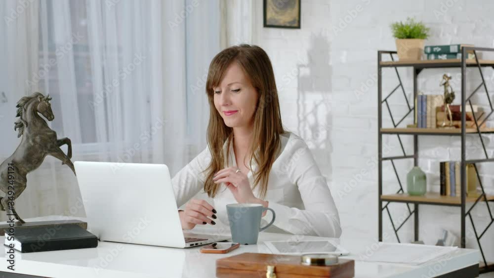 Young business woman working at desk with laptop computer in home office. Young business woman working at desk with laptop computer in home office.
