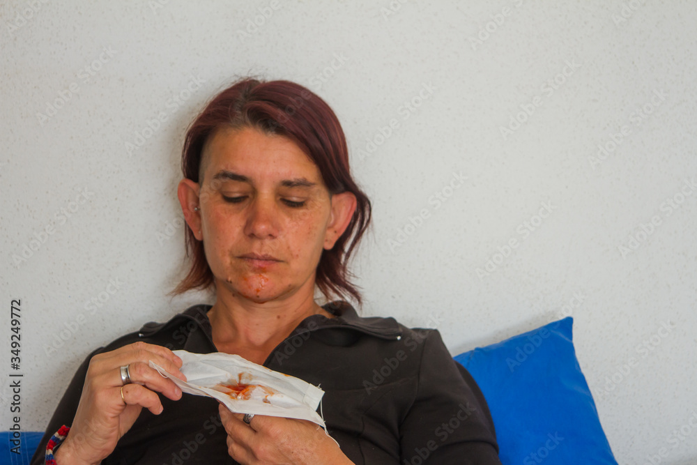 woman on bed spitting coughing blood in protective surgical mask getting dirty with blood woman on bed spitting coughing blood in protective surgical mask getting dirty with blood