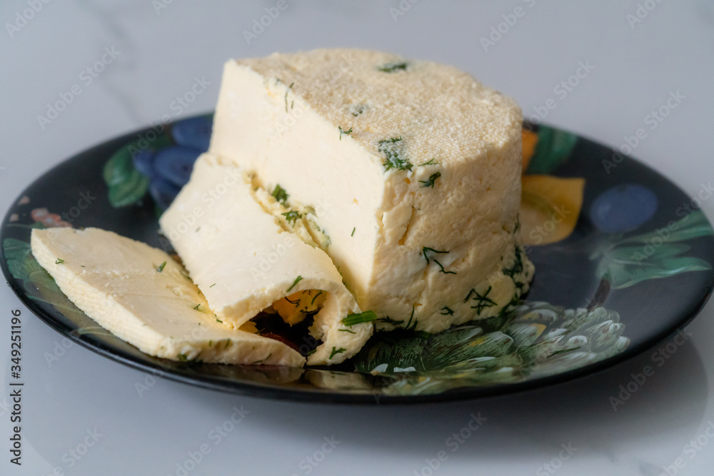a piece of homemade cheese with dill and spices on a black plate