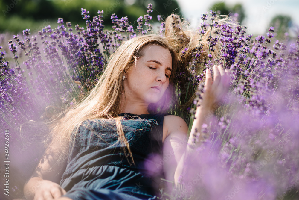 Beautiful girl in dress lying down on purple the lavender field. Beautiful woman in the lavender field on sunset in France. Soft focus. Series. Enjoy on the floral glade, summer nature. Close up.