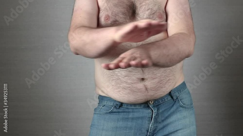 Happy shirtless fat man in jeans dancing in slow motion with hands scissors. Big obese belly shaking. Overeating problem concept