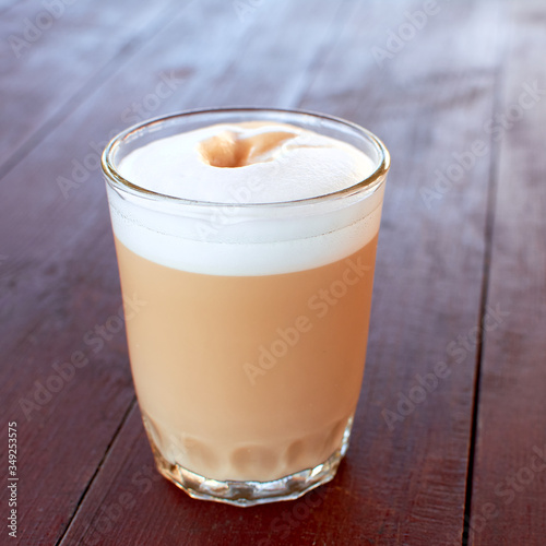 Coffee and milk drink in a glass. Latte or mocha in a glass on a wooden table. Espresso with milk is stolen with airy milk foam