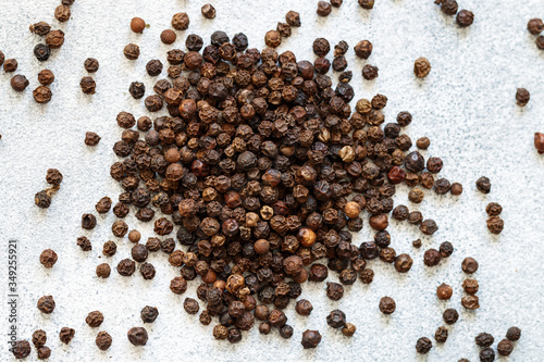 Organic dried Black Peppercorns on light concrete or stone background close-up. Pepper. Spices and seasonings. Selective focus, top view