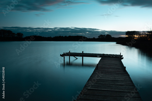 Wooden jetty on a calm blue lake, sky after sunset