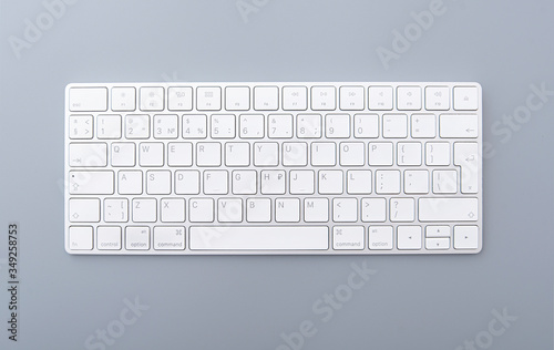 Close-up white keyboard on gray desk, top view of modern computer keyboard isolated on gray background 