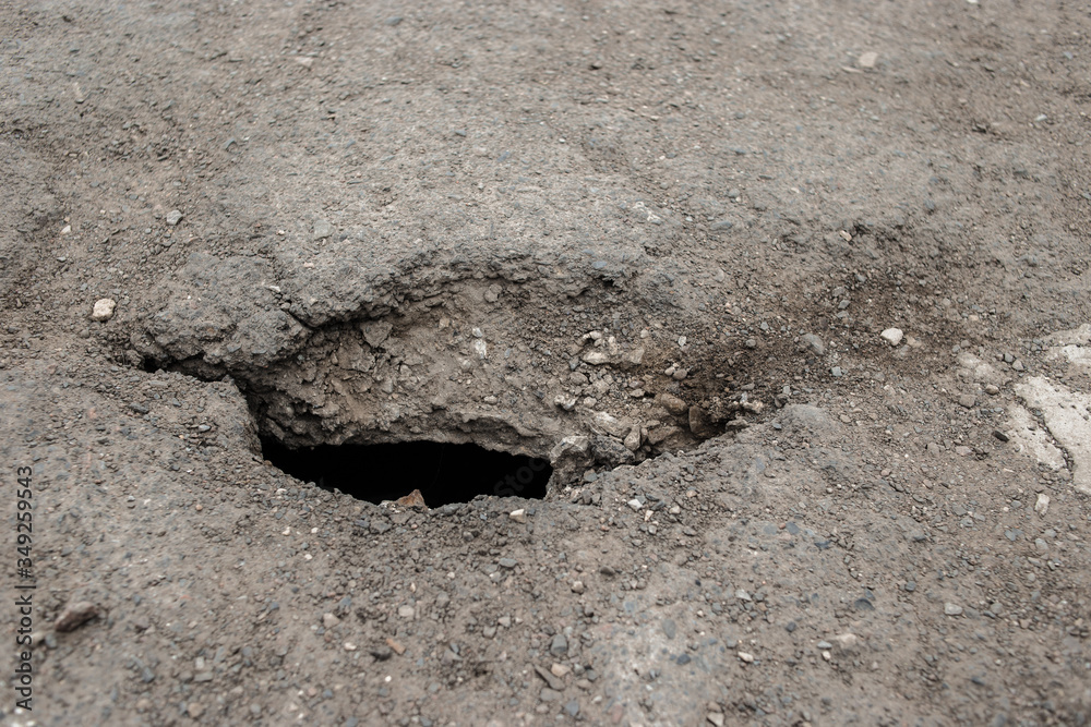 Naklejka premium A hole in the asphalt, Danger. Road destruction
