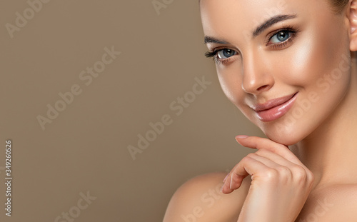 Beautiful young woman with clean fresh skin touching her face . Girl facial treatment . Cosmetology , beauty and spa . Female model, care concept