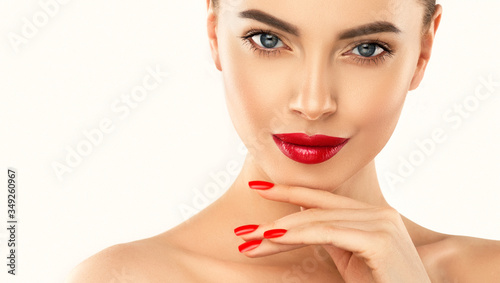 Beautiful girl showing red manicure nails & lips. Woman Makeup, beauty and cosmetics