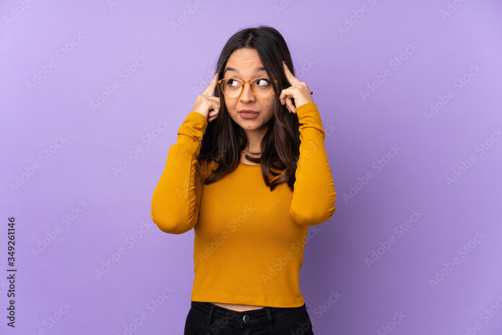 Young mixed race woman isolated on purple background having doubts and thinking Young mixed race woman isolated on purple background having doubts and thinking