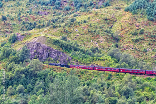 Jacobite steam express approaching Glenfinnan viaduct in Scotland, United Kingdom. The train and viaduct is famous for it is appearance in Harry Potter movies photo