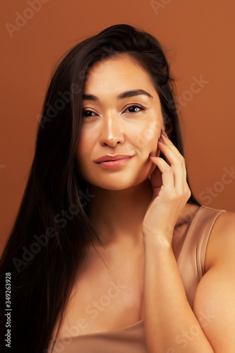 young pretty asian woman cheerful smiling posing on warm brown background, lifestyle people concept