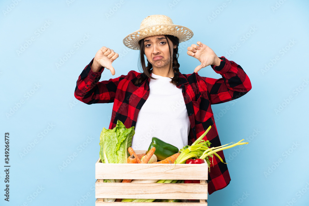 Young farmer Woman holding fresh vegetables in a wooden basket showing thumb down