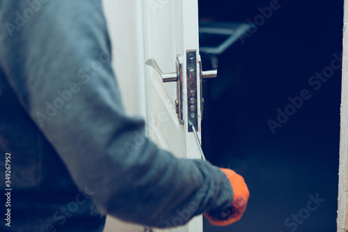 Handyman repair the door lock in the room. Man fixing lock with screwdriver, close-up of repairing door, professional locksmith installing or repairing a new deadbolt lock on a house or office.