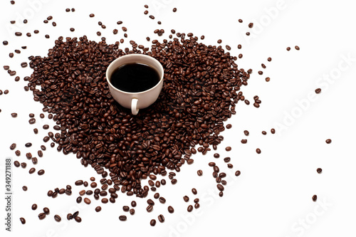scattered coffee beans on a white empty background. heart-shaped coffee beans. a Cup of black coffee on a background of coffee beans. the Cup stands on a coffee handful in the shape of a heart
