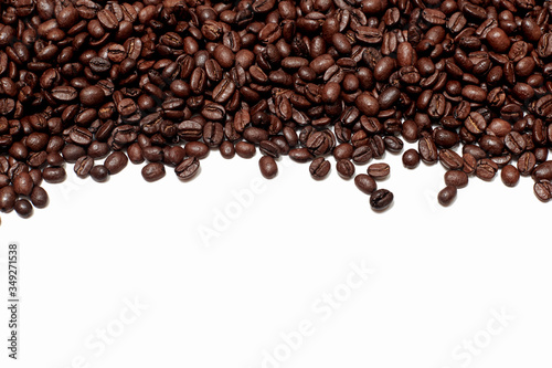background of roasted brown coffee beans. the texture of coffee or abstraction for the background. a handful of coffee beans is placed on top along the edge of the frame, falling from above