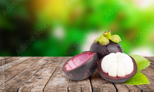 Fresh ripe mangosteen fruits on wooden table with mangosteen tree background