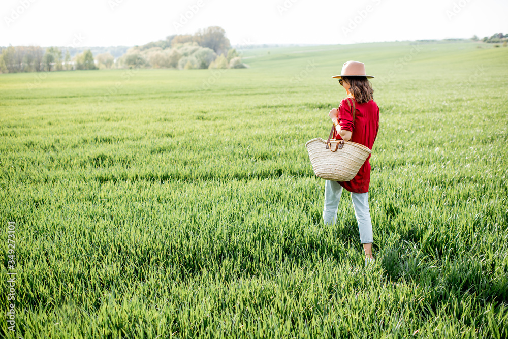 Stylish woman walking with bag on the greenfield, enjoying springtime and nature. Concept of a carefree lifestyle and beauty on nature Stylish woman walking with bag on the greenfield, enjoying springtime and nature. Concept of a carefree lifestyle and beauty on nature