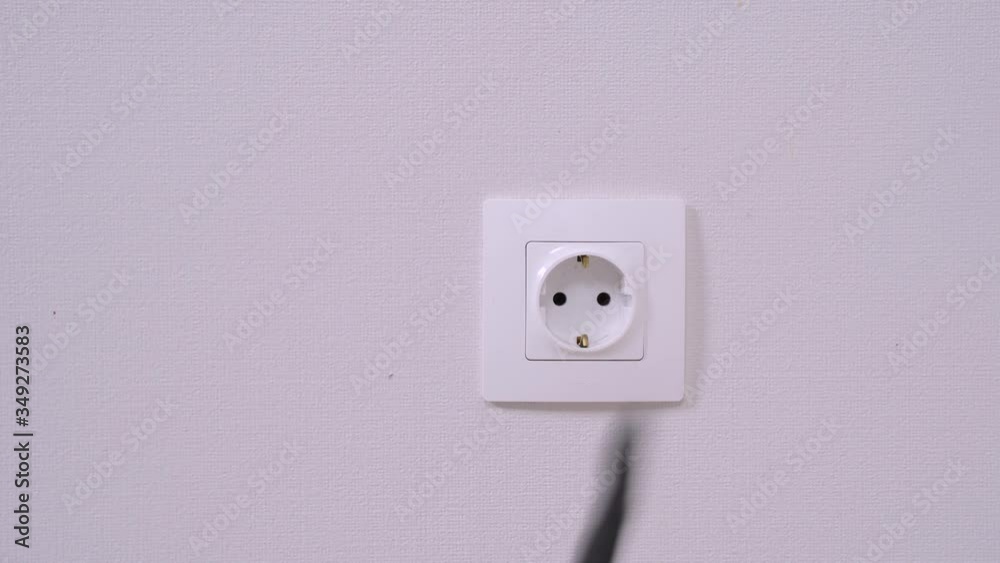 Human points with finger and touches the plug of cord in electrical socket on white wall, smart obedient dachshund dog pulls out wire, turning off device or household appliance, front view, close up. Human points with finger and touches the plug of cord in electrical socket on white wall, smart obedient dachshund dog pulls out wire, turning off device or household appliance, front view, close up.