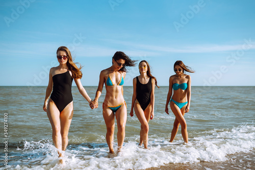Happy four girls having fun and running along beach. Young women enjoying on beach holiday. Summer, relax and lifestyle concept.