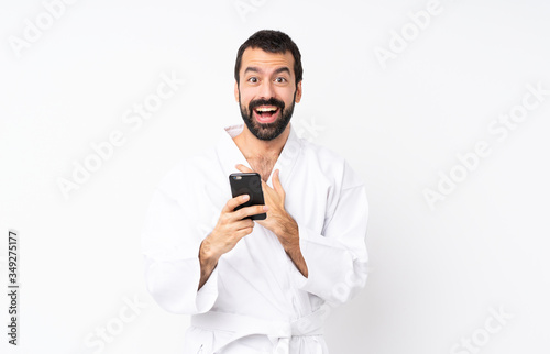 Young man doing karate over isolated white background surprised and sending a message