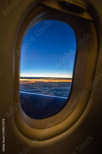 Sunset view over the clouds from the porthole of an airplane
