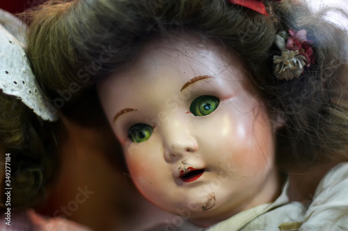 Boneca antiga de porcelana em fotografia close up com detalhes nas pinturas, olhos e cabelo.  Profundidade de campo reduzida. Brinquedo retrô bem conservado de antiquário.