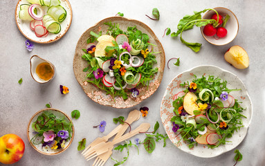 Delicious summer salad with edible flowers, vegetables, fruit, microgreens and cheese. Clean and healthy eating concept. Top view.