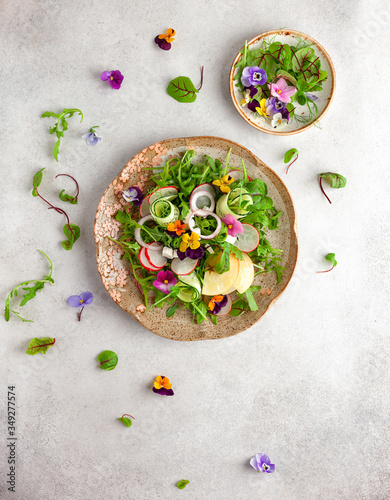 Delicious summer salad with edible flowers, vegetables, fruit, microgreens and cheese. Clean and healthy eating concept. Top view. photo