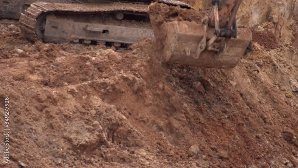 crawler excavator digging the earth with a bucket at a construction site, close-up, industry. crawler excavator digging the earth with a bucket at a construction site, close-up, industry.