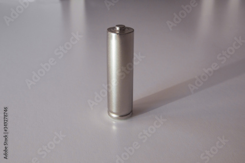 A gray AA model battery stands upright on a white background