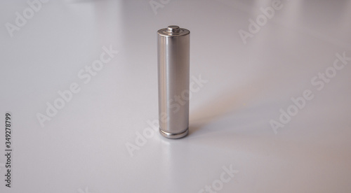 A gray AA model battery stands upright on a white background