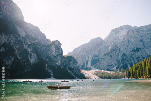 Newlyweds sail in a wooden boat on the Lago di Braies in Italy. Wedding in Europe, on Braies lake. Wedding couple - The groom rows with wooden oars, the bride sits opposite.