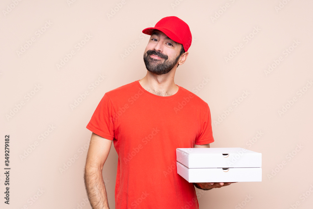 Young man holding a pizza over isolated background laughing Young man holding a pizza over isolated background laughing