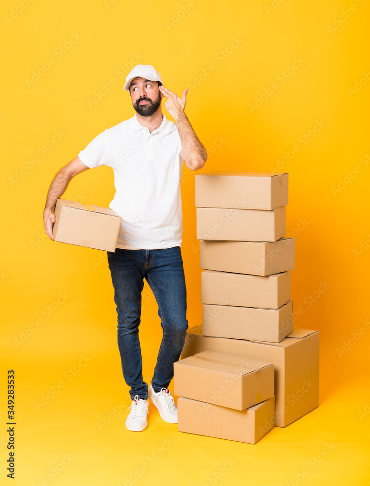 Full-length shot of delivery man among boxes over isolated yellow background with problems making suicide gesture Full-length shot of delivery man among boxes over isolated yellow background with problems making suicide gesture