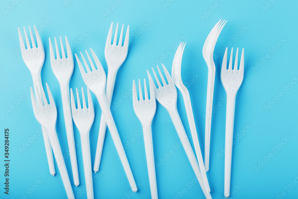 White plastic forks of disposable tableware on a blue background. White plastic forks of disposable tableware on a blue background.