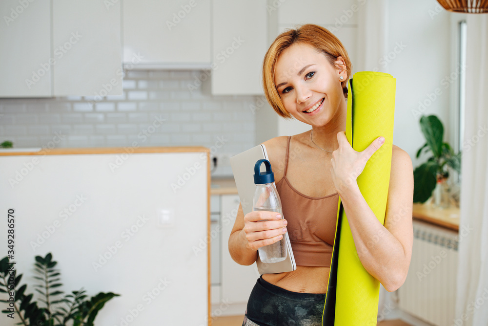 Portait of a fit happy woman smiling, holding yoga mat and water bottle Portait of a fit happy woman smiling, holding yoga mat and water bottle